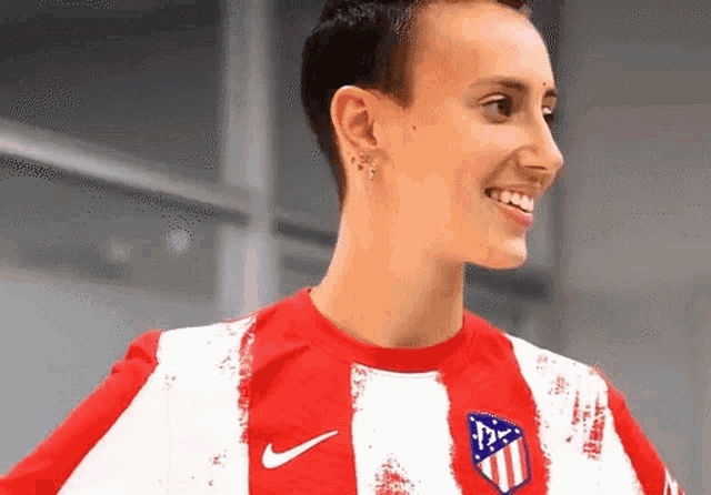 a woman wearing a red and white striped nike shirt smiles