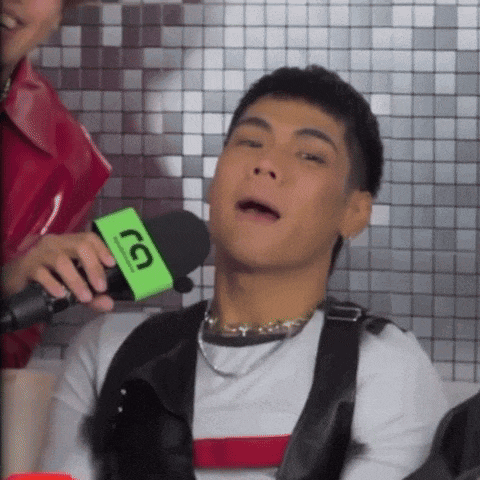 a man is talking into a microphone with a green sticker that says tg on it .