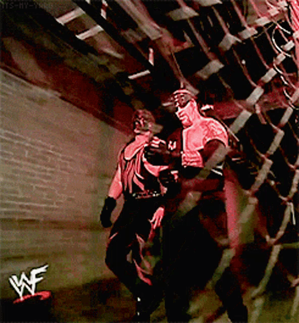 two wrestlers in a dark room with a wwe logo in the corner