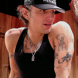 a man wearing a black tank top and a black hat with pmc on it