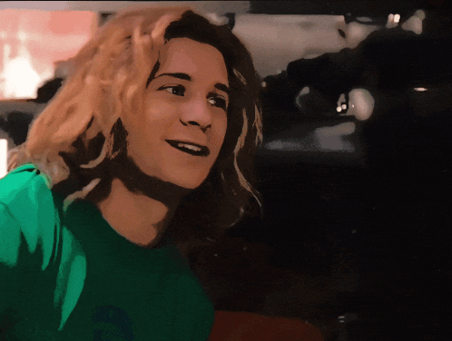 a woman with long blonde hair wearing a green shirt that says a on it