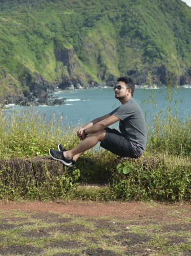 a man is sitting on a rock overlooking a body of water