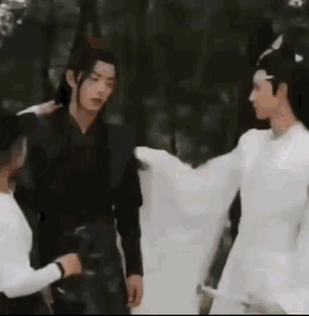 a group of men are standing next to each other in a forest holding hands .
