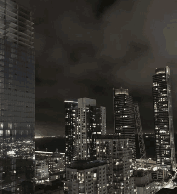 a view of a city at night with a few buildings lit up including one that says ' allianz ' on it