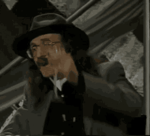 a man in a hat is holding a wine glass in his hand