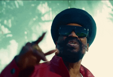 a man wearing sunglasses and a hat is pointing at the camera