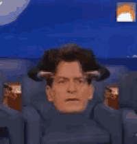 a man is sitting in a chair holding his head .