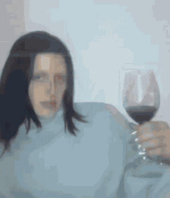 a woman is holding a glass of red wine in her hand .
