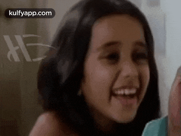 a little girl is laughing and smiling while looking at the camera .