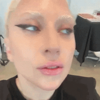 a close up of a woman 's face with a black shirt on and a table in the background .