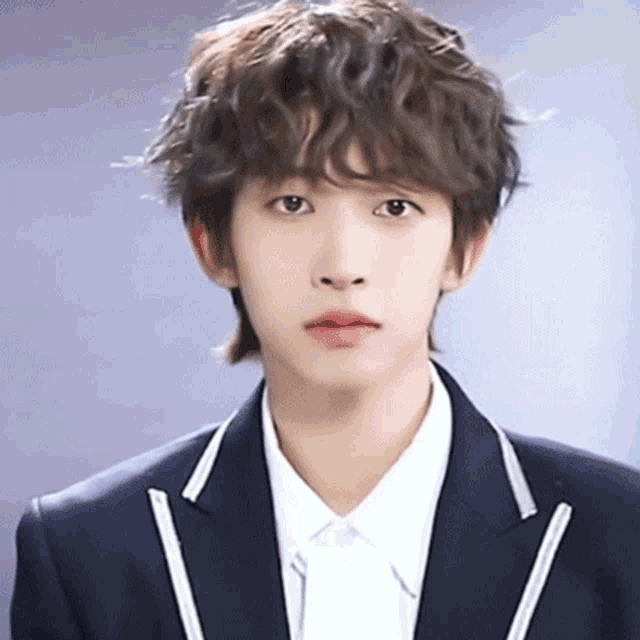 a young man with curly hair wearing a suit and a white shirt