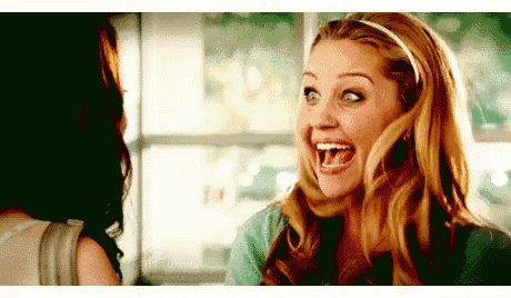 a woman is laughing with her mouth open while looking at another woman .