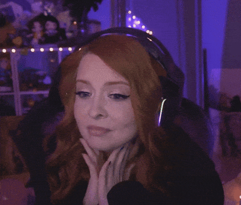 a woman with red hair is wearing headphones and waving her hand