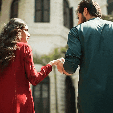 a man and a woman are holding hands in front of a white building