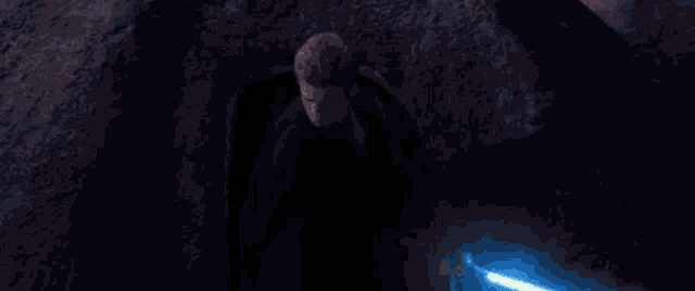 a person is holding a light saber in their hand in the dark .