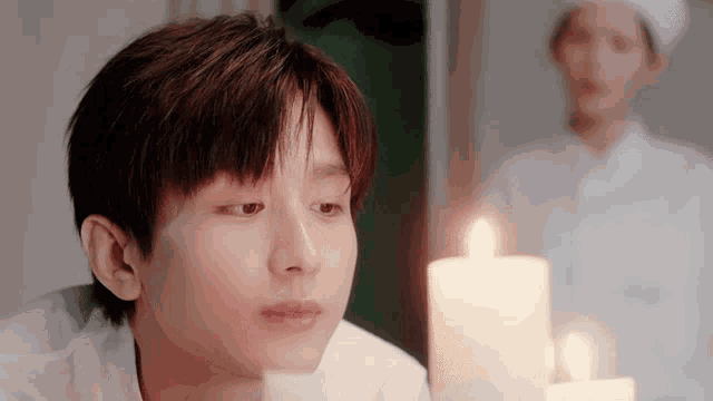 a young man is looking at a lit candle