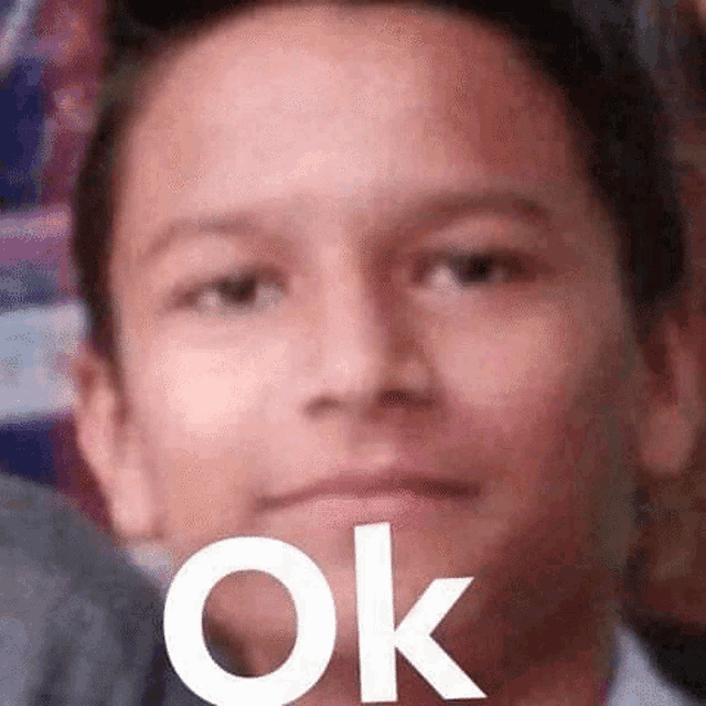 a close up of a young man 's face with the word ok written on it .