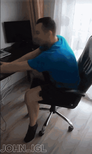a man in a blue shirt sits in an office chair with the name john igl on the bottom right