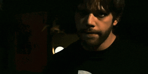a man with a beard is wearing a black shirt with a white circle on it