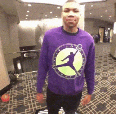 a man wearing a purple sweater with a picture of a basketball player