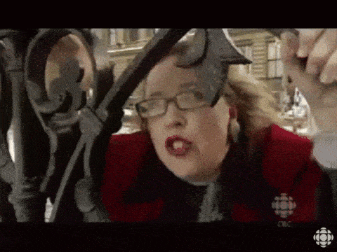 a woman wearing glasses and a red jacket with a cbc logo on her shirt