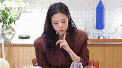 a woman is sitting at a table with a glass of wine and a plate of food .