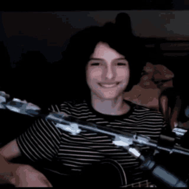 a young man is smiling in front of a microphone while playing a guitar .