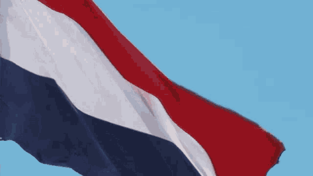 a red white and blue flag with a blue sky in the background