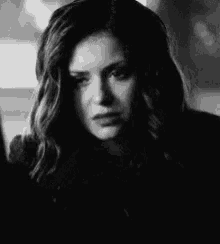 a black and white photo of a woman with her eyes closed and a sad look on her face .