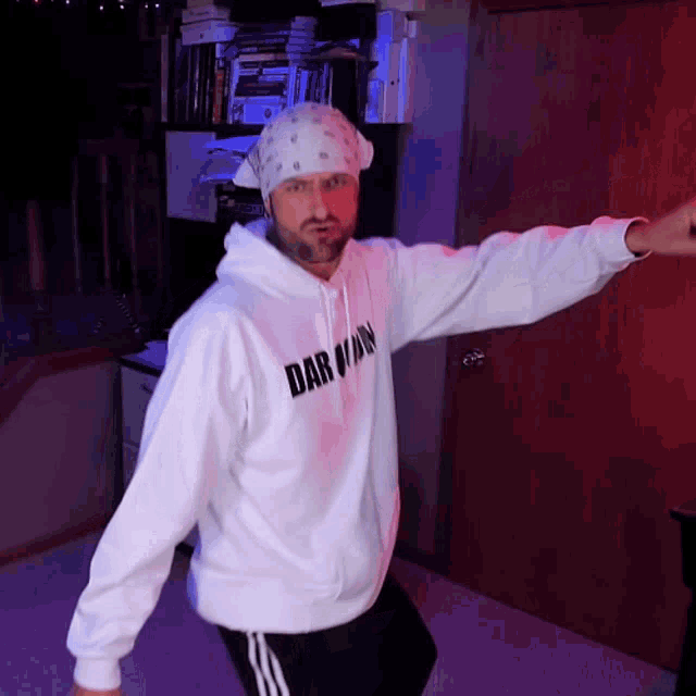 a man wearing a darwin hoodie is dancing in a room