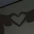 a couple of hands making a heart shape with their shadows .