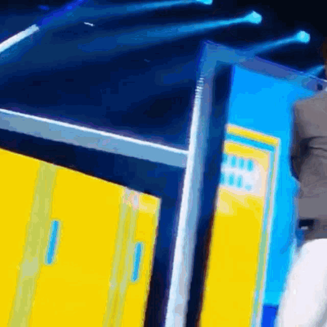 a man in a suit is standing on a stage in front of a yellow wall .