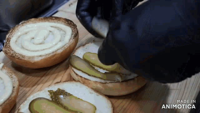 a person is making a hamburger with pickles and mayonnaise