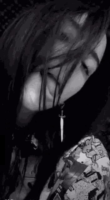 a black and white photo of a woman wearing earrings with a sword hanging from her ear .