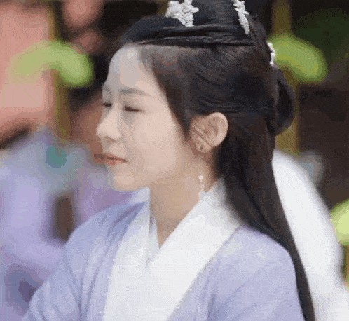 a close up of a woman wearing a purple and white dress