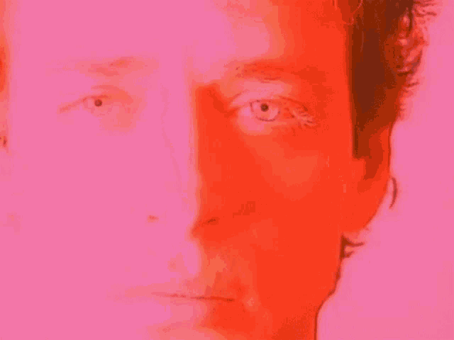 a close up of a man 's face with a pink background