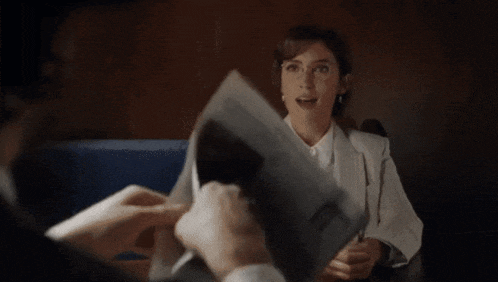 a man is holding a piece of paper in front of a woman in a suit .