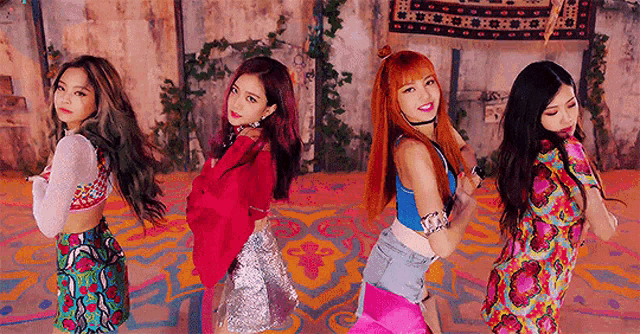 a group of girls are standing next to each other on a colorful floor in a room .