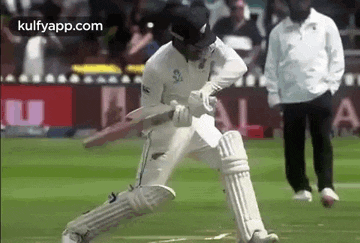 a cricket player is swinging a bat at a ball while standing on a field .