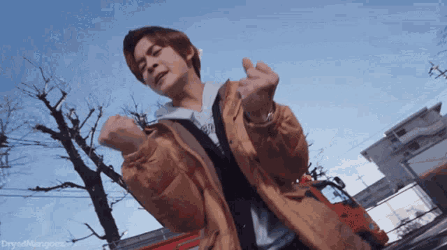 a man in a tan jacket is standing in front of a red truck and a blue sky