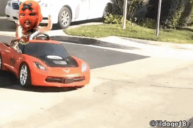 a man in a mask is driving a toy car on a street