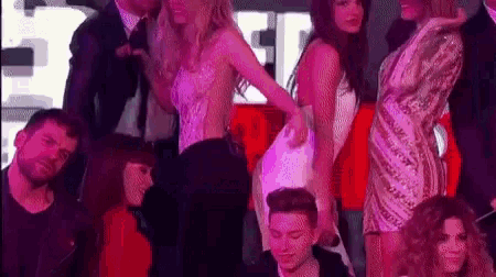 a group of people are standing around a woman in a white dress in a club .