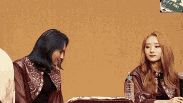 two women are sitting next to each other and one has a bottle of water in her hand