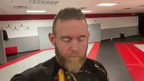 a man with a beard is standing in a room with his eyes closed