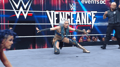 a female wrestler is kneeling down in front of a sign that says vengeance on it