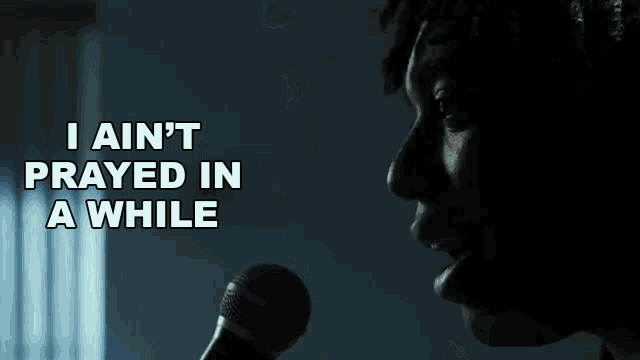 a man singing into a microphone with the words " i ain 't prayed in a while " above him