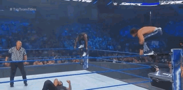 two men are wrestling in a wrestling ring while a referee runs behind them .