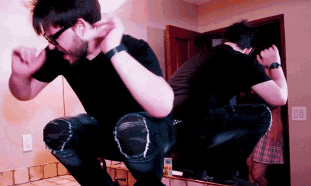 a man squatting in front of a mirror with a woman behind him