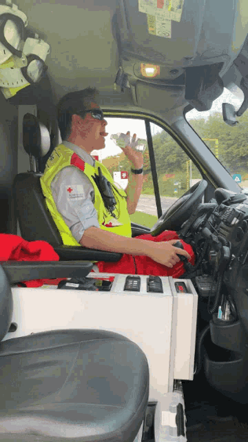 a man in a yellow vest with a red cross on it drinks water
