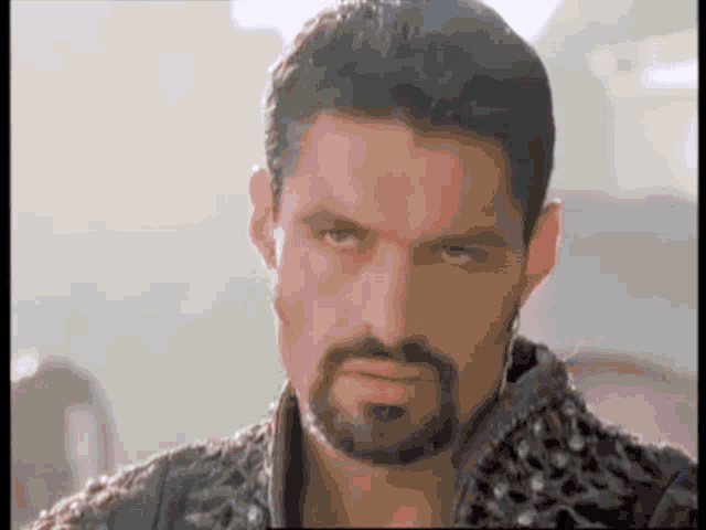 a man with a beard is making a serious face and looking at the camera .